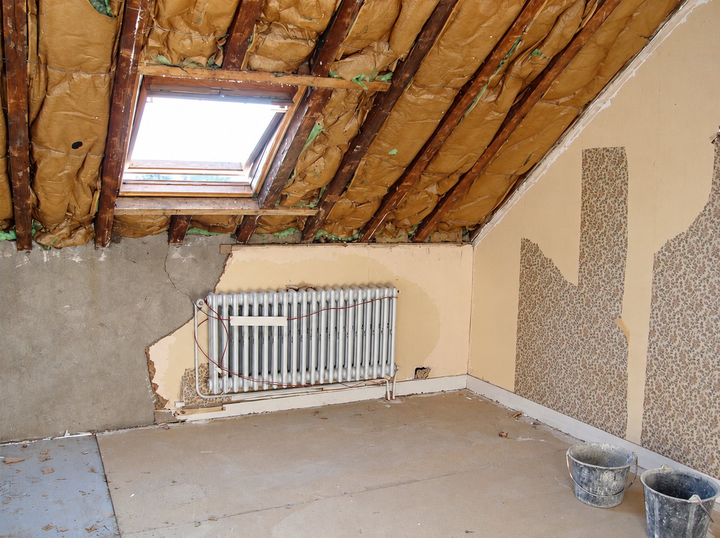 Combles en chantier, isolant apparent, radiateur et fenêtre de toit