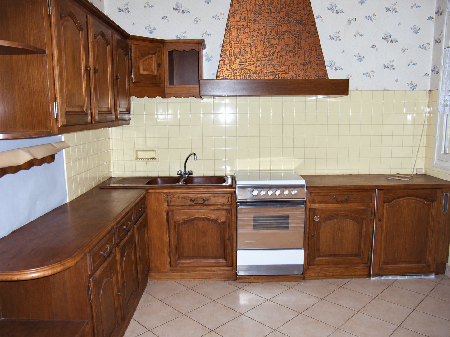 Cuisine ancienne en bois foncé avec hotte cuivrée et carrelage