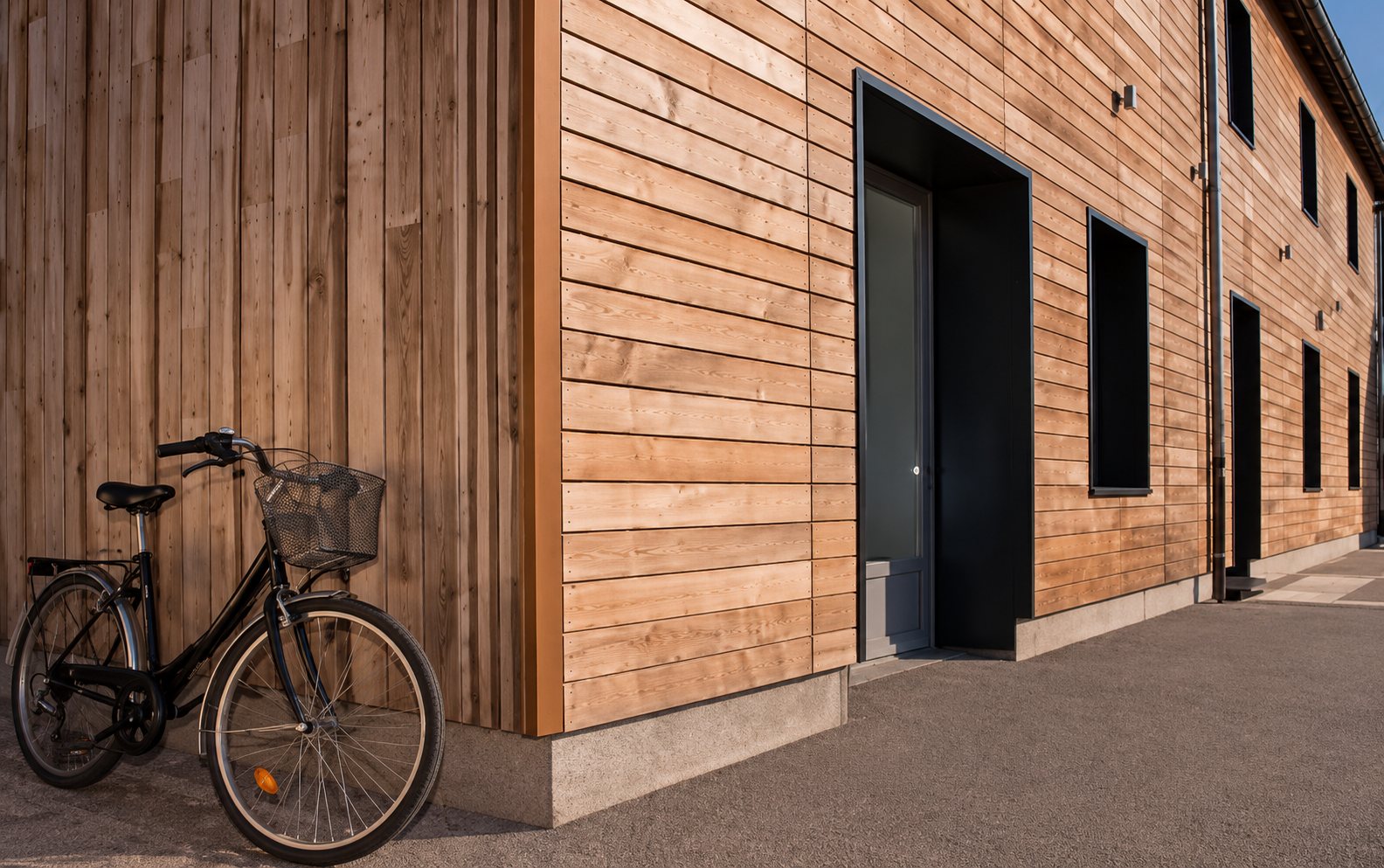 Façade en bardage bois avec vélo appuyé contre le mur