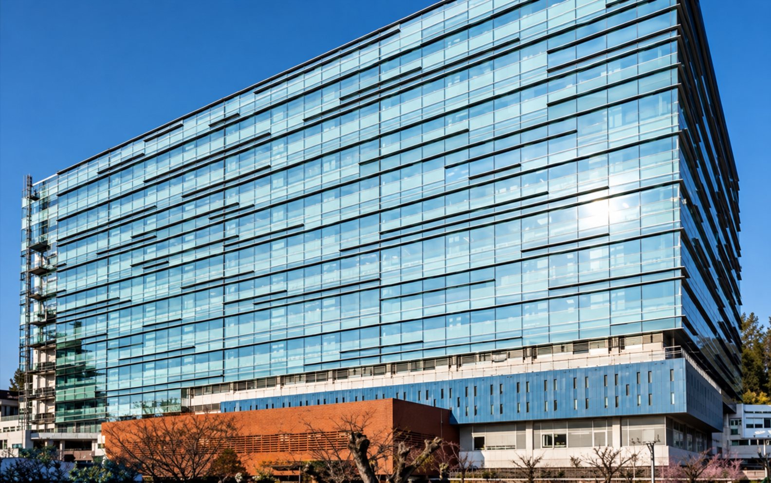 Grand immeuble de bureaux moderne à façade entièrement vitrée sous ciel bleu