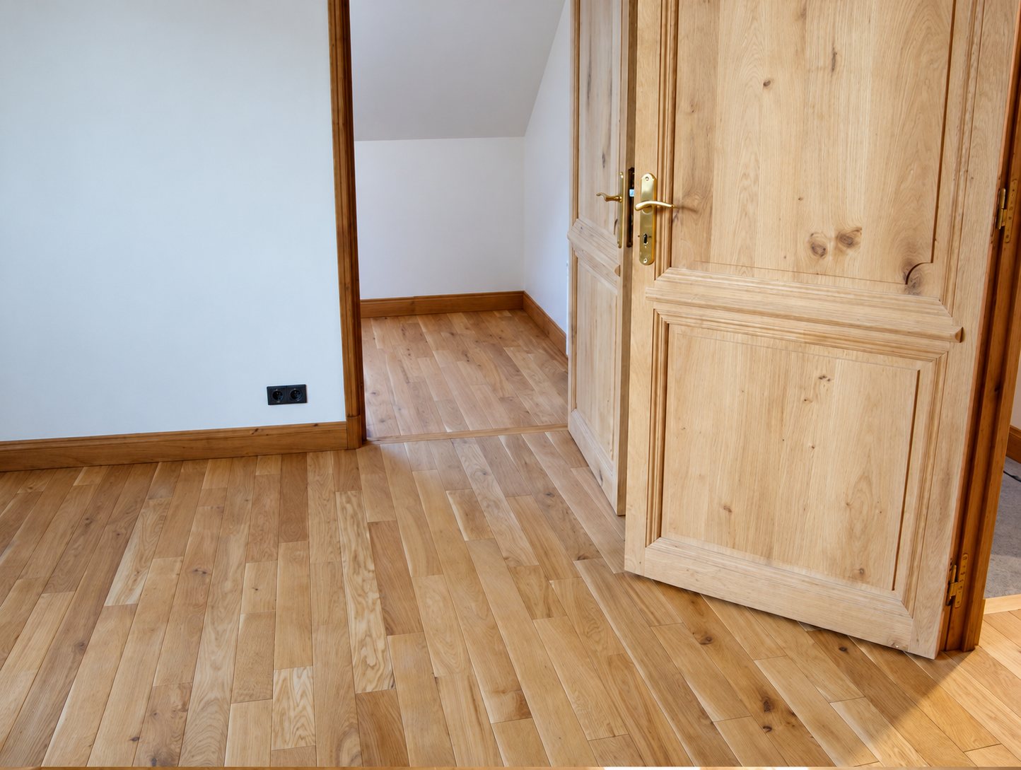 Parquet en chêne en cours de pose dans une chambre mansardée aux portes en bois