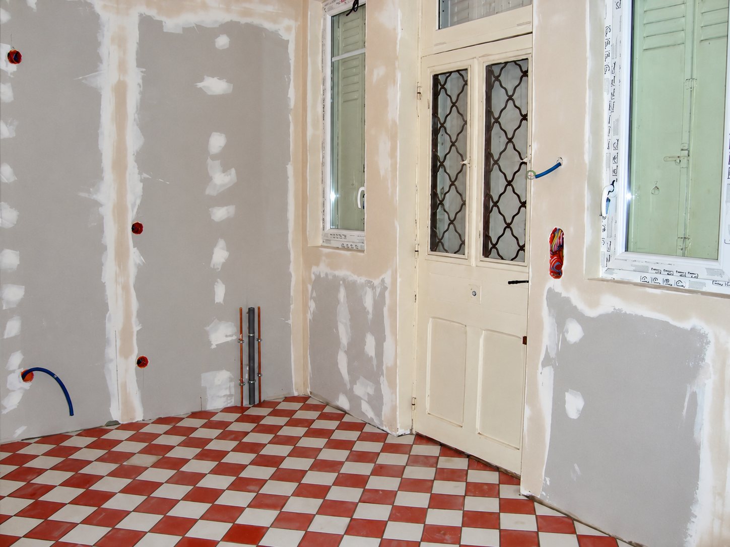 Pièce en rénovation avec plaques de plâtre et carrelage en damier rouge