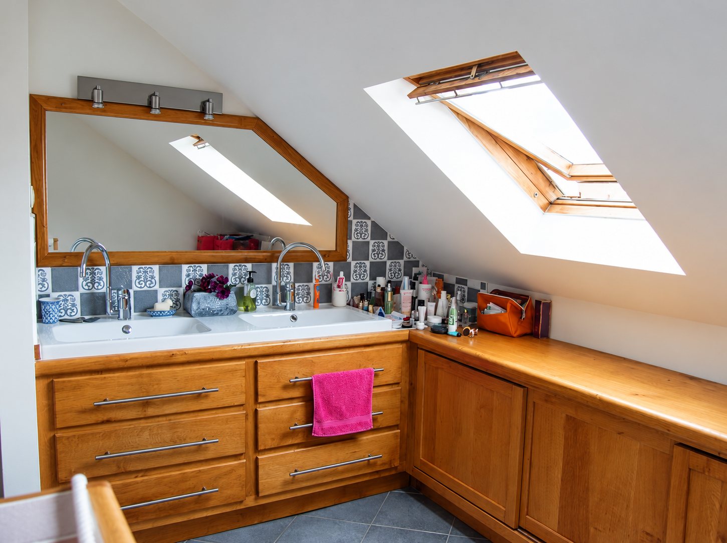 Salle de bain sous les combles avec meuble en bois à double vasque